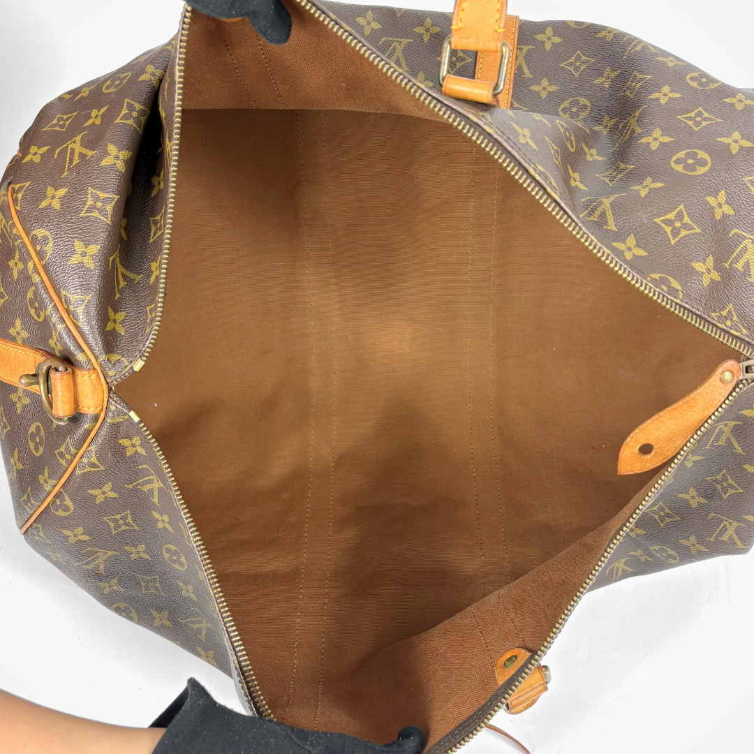 Louis Vuitton monogram travel bag with brown handles on a white background