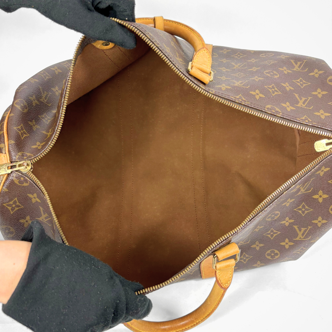 Louis Vuitton monogram travel bag with brown handles and strap on a white background