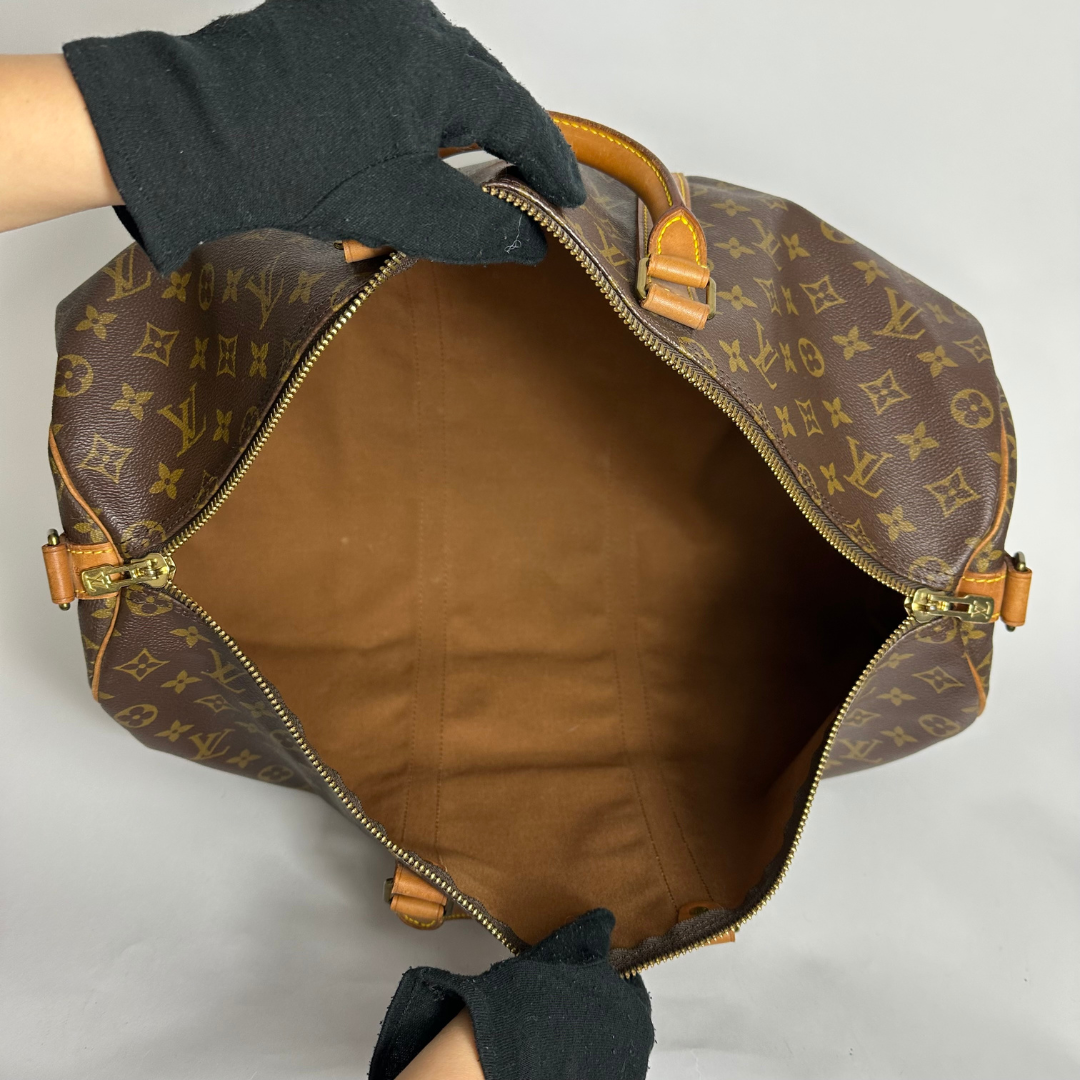 Louis Vuitton monogram duffel bag with tan handles on a white background