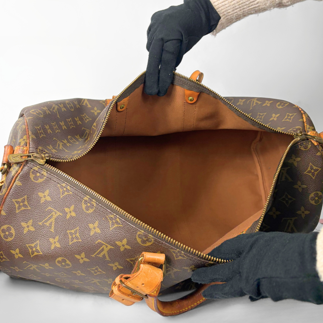 Braune Reisetasche mit Monogrammmuster auf weißem Hintergrund