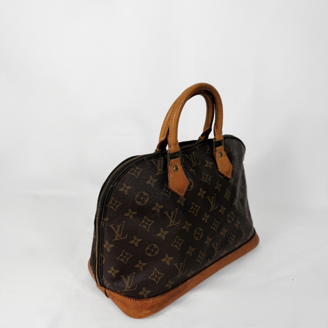 A Louis Vuitton monogram canvas dome handbag with tan leather handles and trim, photographed on a white studio background.