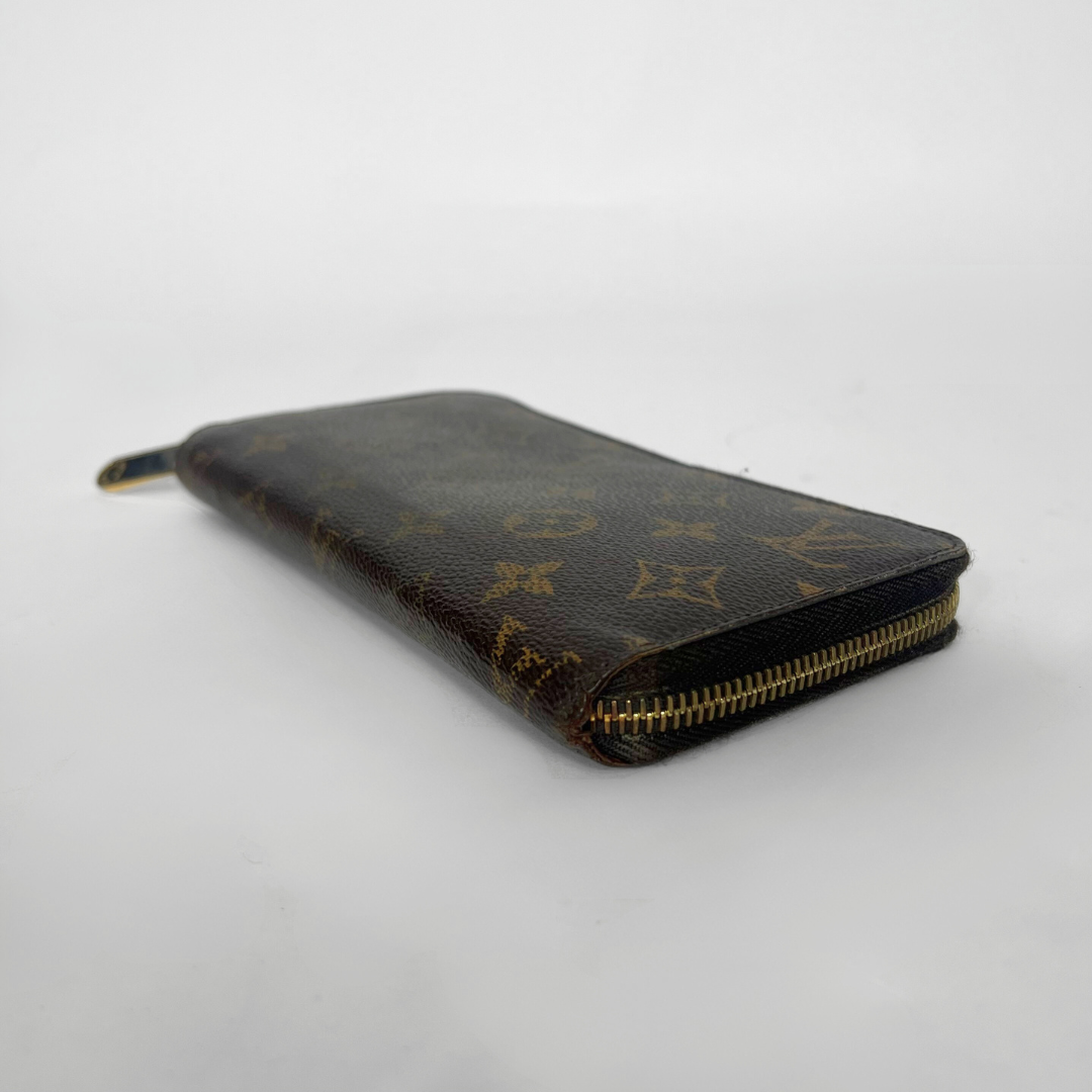 Louis Vuitton wallet with monogram pattern on a light gray background