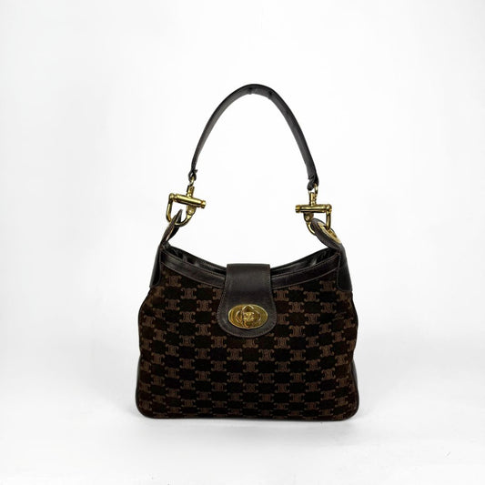 Brown patterned handbag with gold accents on a white background