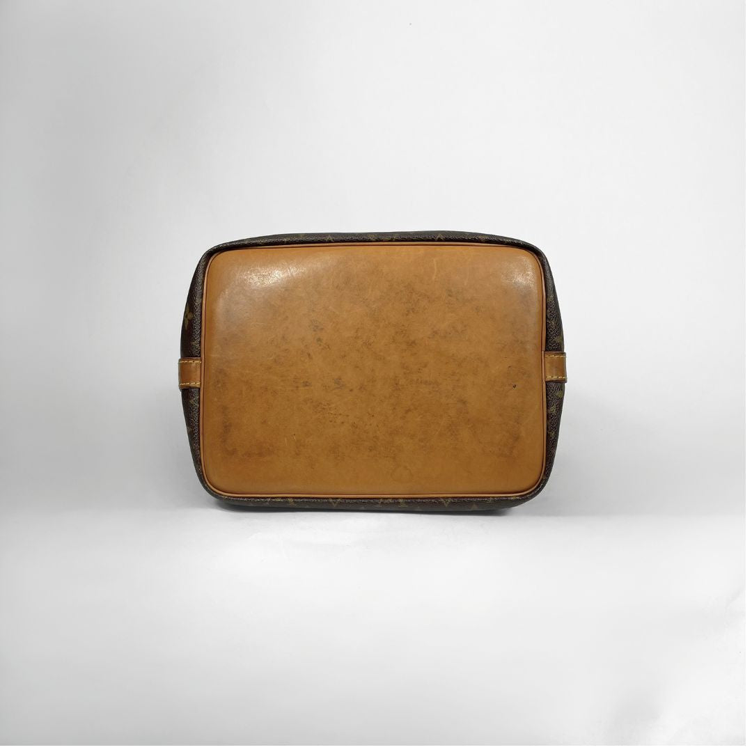 A vintage Louis Vuitton toiletry bag in the signature brown monogram canvas, featuring a tan leather front panel and dark brown patterned sides, photographed against a neutral light gray background.