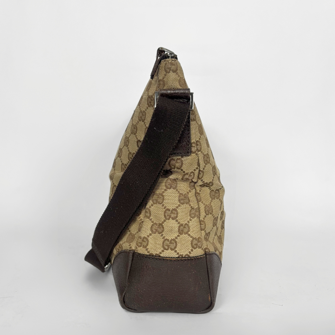 Beige and brown patterned bag with a black strap on a light gray background