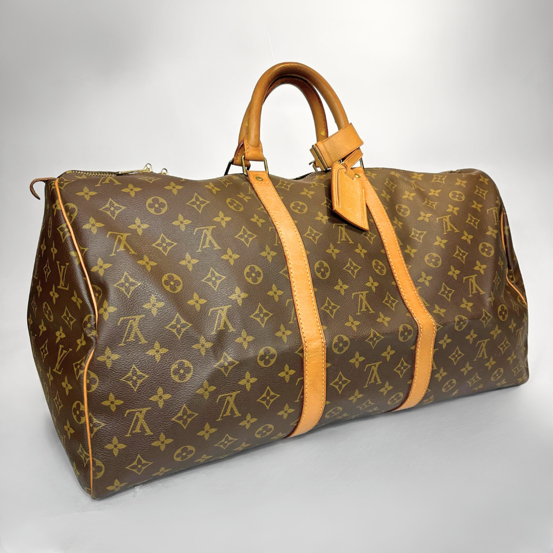 Brown travel bag with yellow monogram pattern on a light gray background