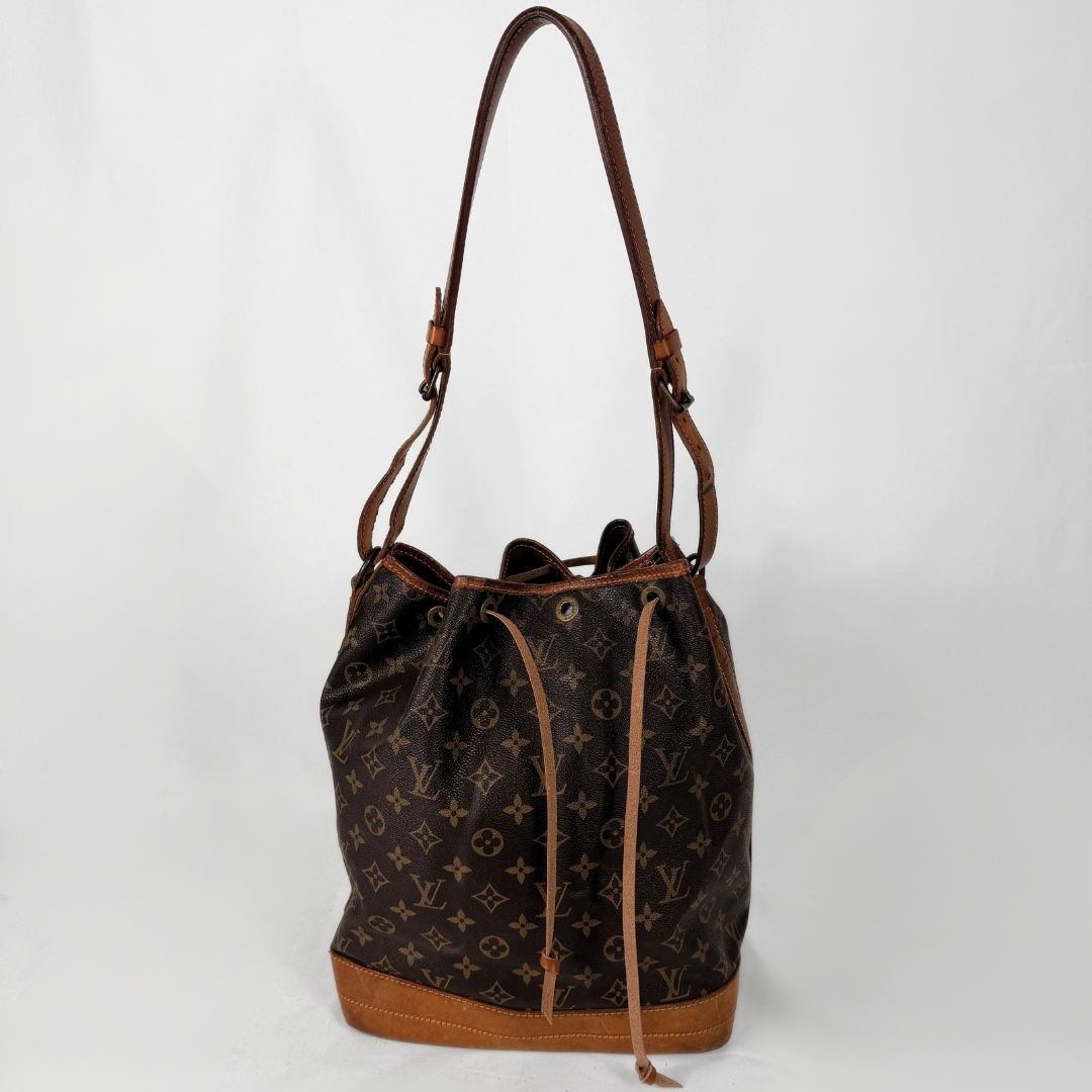 Louis Vuitton monogram canvas bucket bag with brown leather trim and shoulder strap, shown against a plain white background.