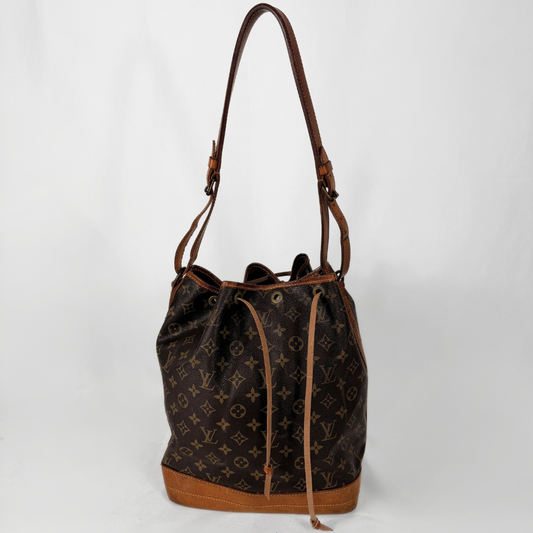 Louis Vuitton μονόγραμμα καμβάς bucket bag με καφέ δερμάτινη επένδυση και λουράκι ώμου, σε απλό λευκό φόντο.