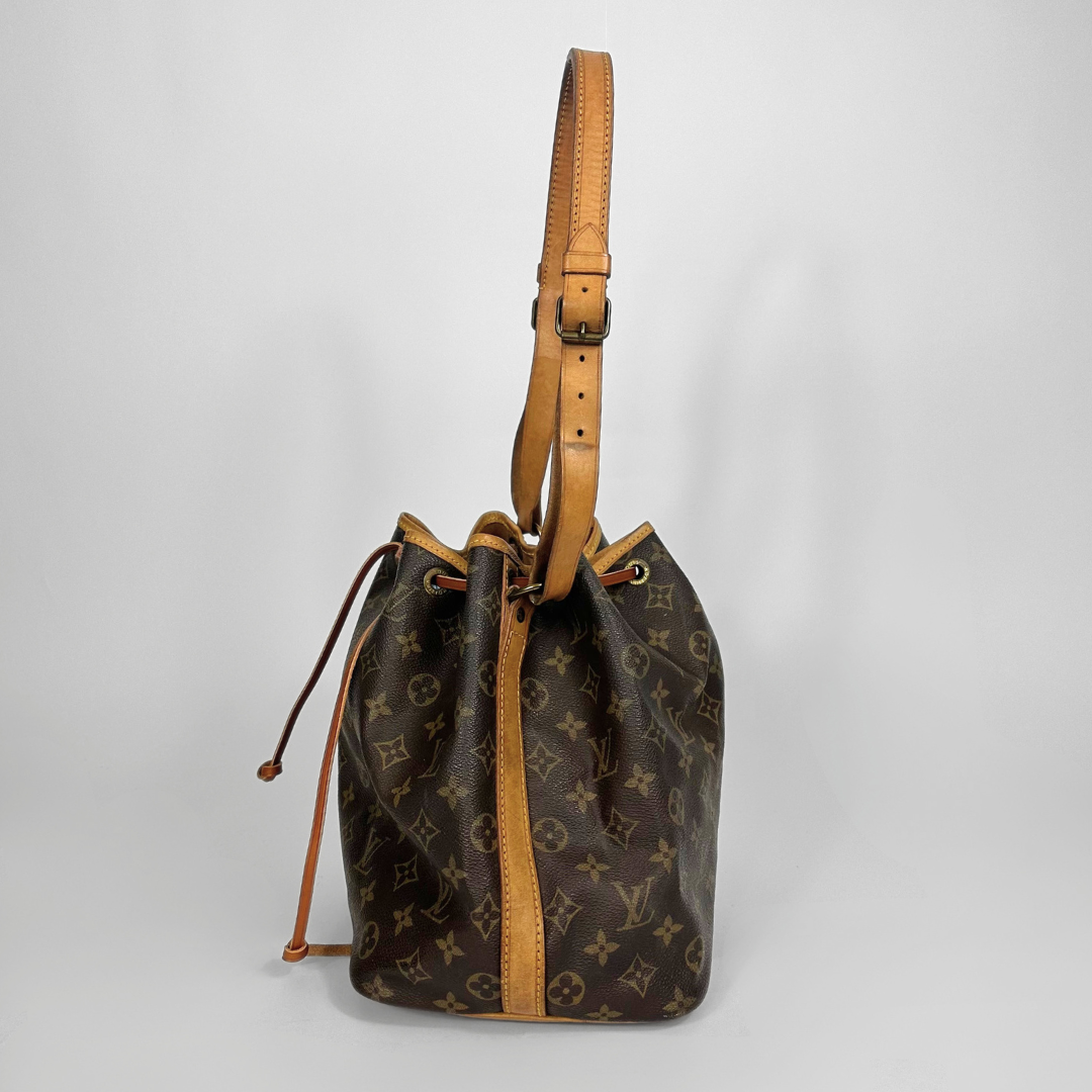 Brown monogram handbag with tan leather straps on a light gray background