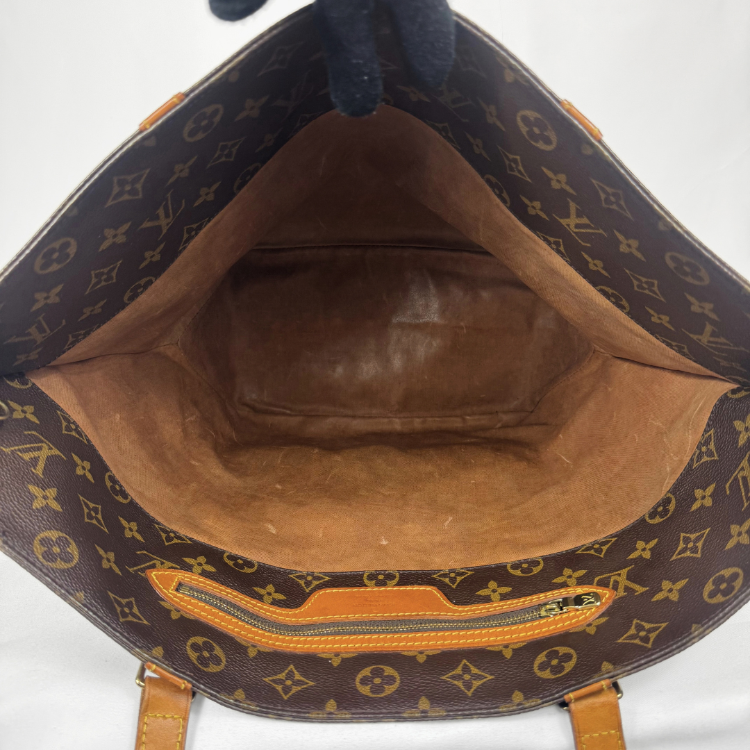 Open Louis Vuitton monogram tote bag showing the brown leather interior, suede-like lining, and a zippered pocket on the bottom rim.
