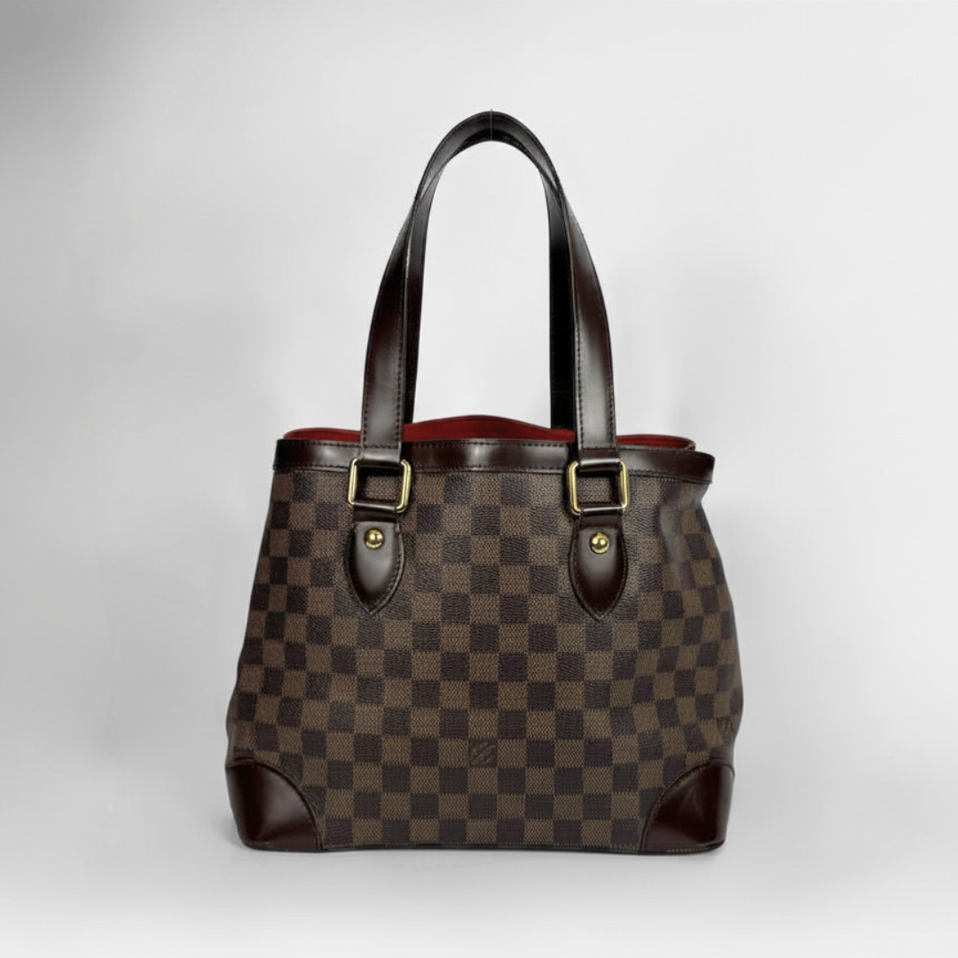 A Louis Vuitton handbag in Damier Ebene canvas with dark brown leather handles and trim, featuring gold-tone hardware, set against a neutral light gray background.