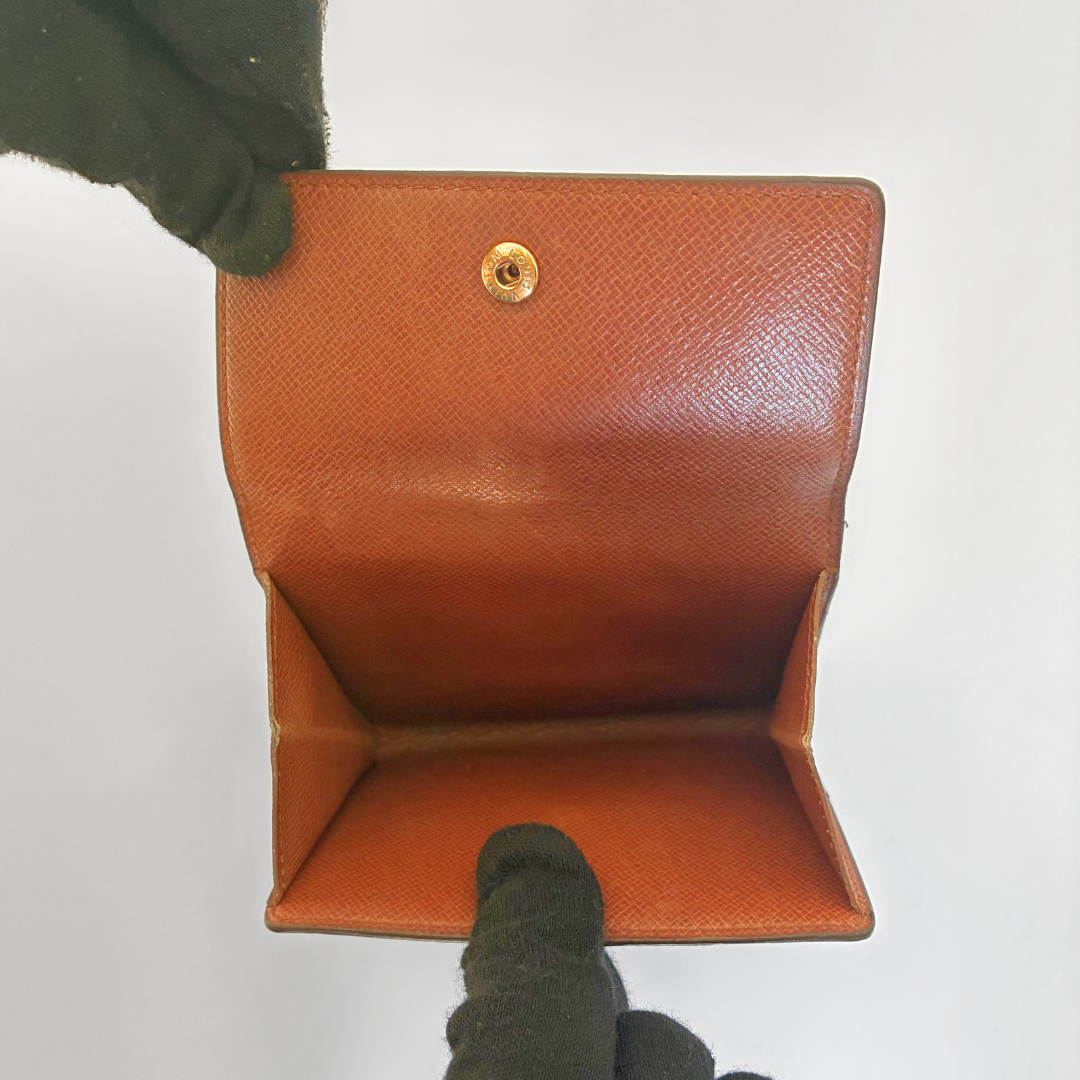 Braune Ledergeldbörse, gehalten von einer behandschuhten Hand vor weißem Hintergrund