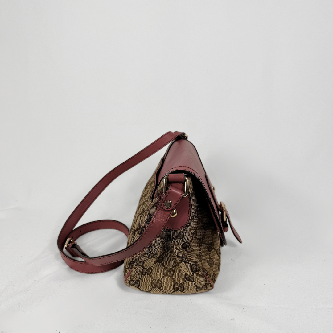 A vintage Gucci shoulder bag in brown GG Supreme canvas with burgundy leather trim and strap, shown from a side angle on a white background.
