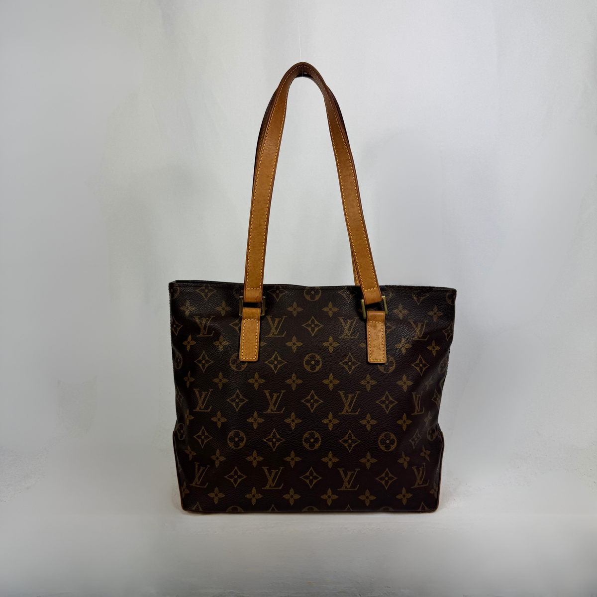 A Louis Vuitton monogram canvas tote bag with tan leather shoulder straps, photographed against a plain light gray background.
