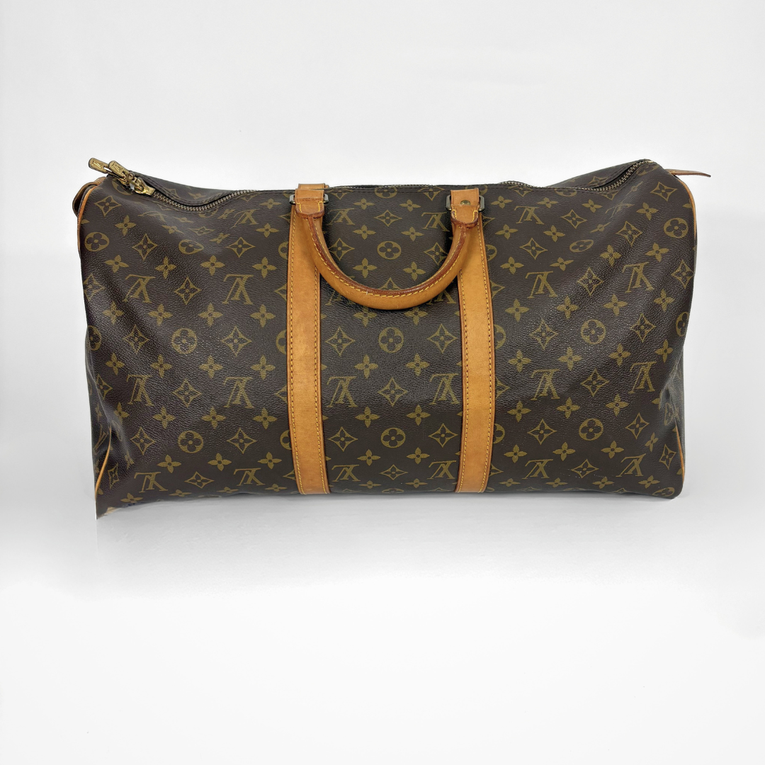 Brown travel bag with tan handles and monogram pattern on a white background