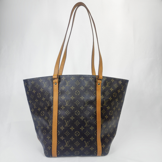 Louis Vuitton Sac cabas en toile monogrammée avec bandoulières et finitions en cuir beige, photographié sur fond blanc en studio.