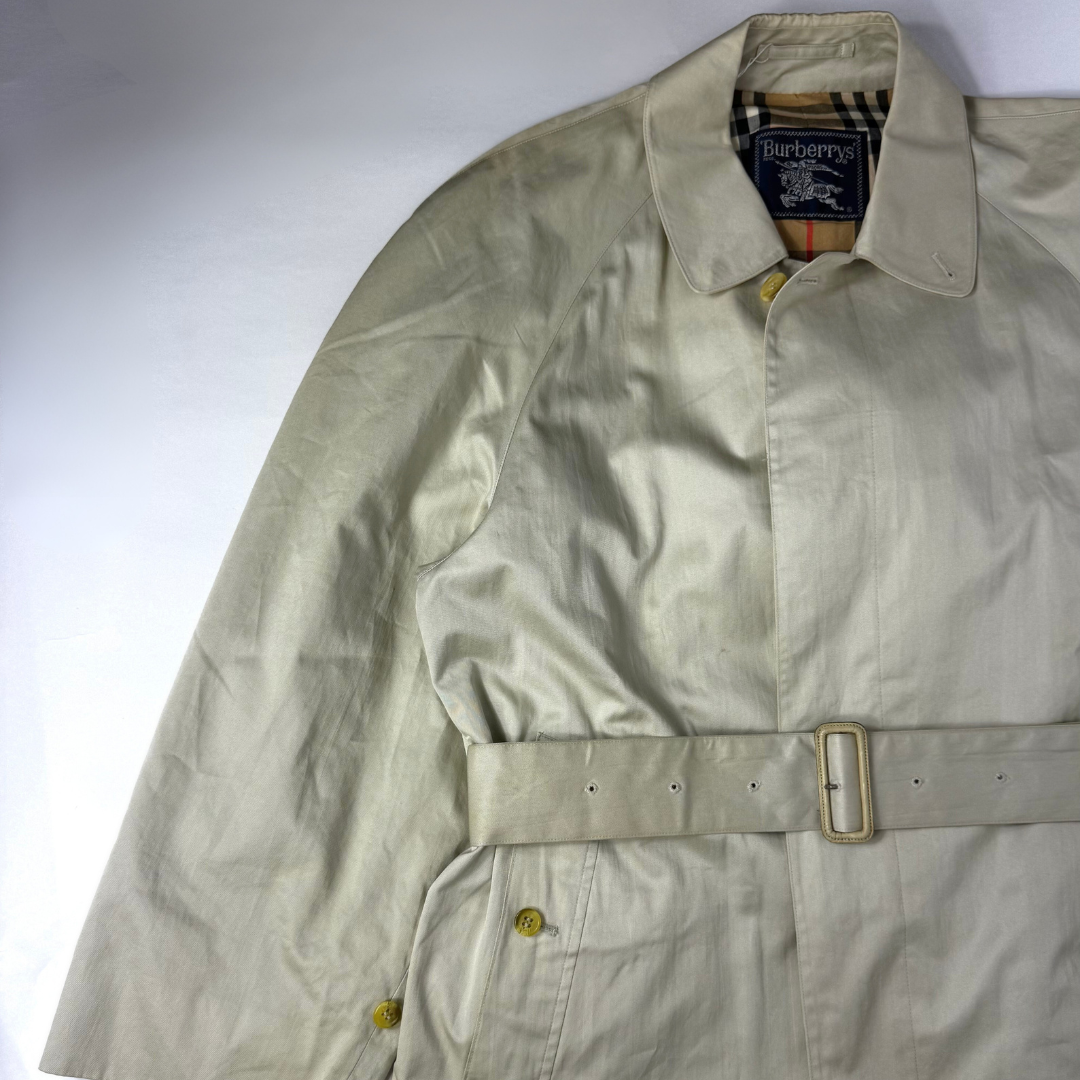 Beigefarbener Trenchcoat, getragen von einer Person vor weißem Hintergrund