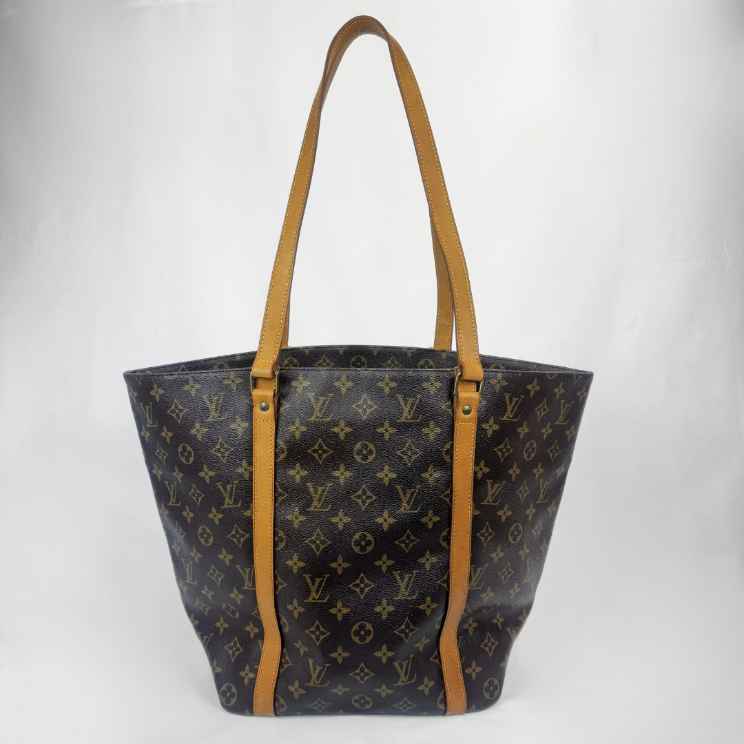 A Louis Vuitton monogram canvas tote bag with tan leather shoulder straps and trim, photographed against a plain light gray background.