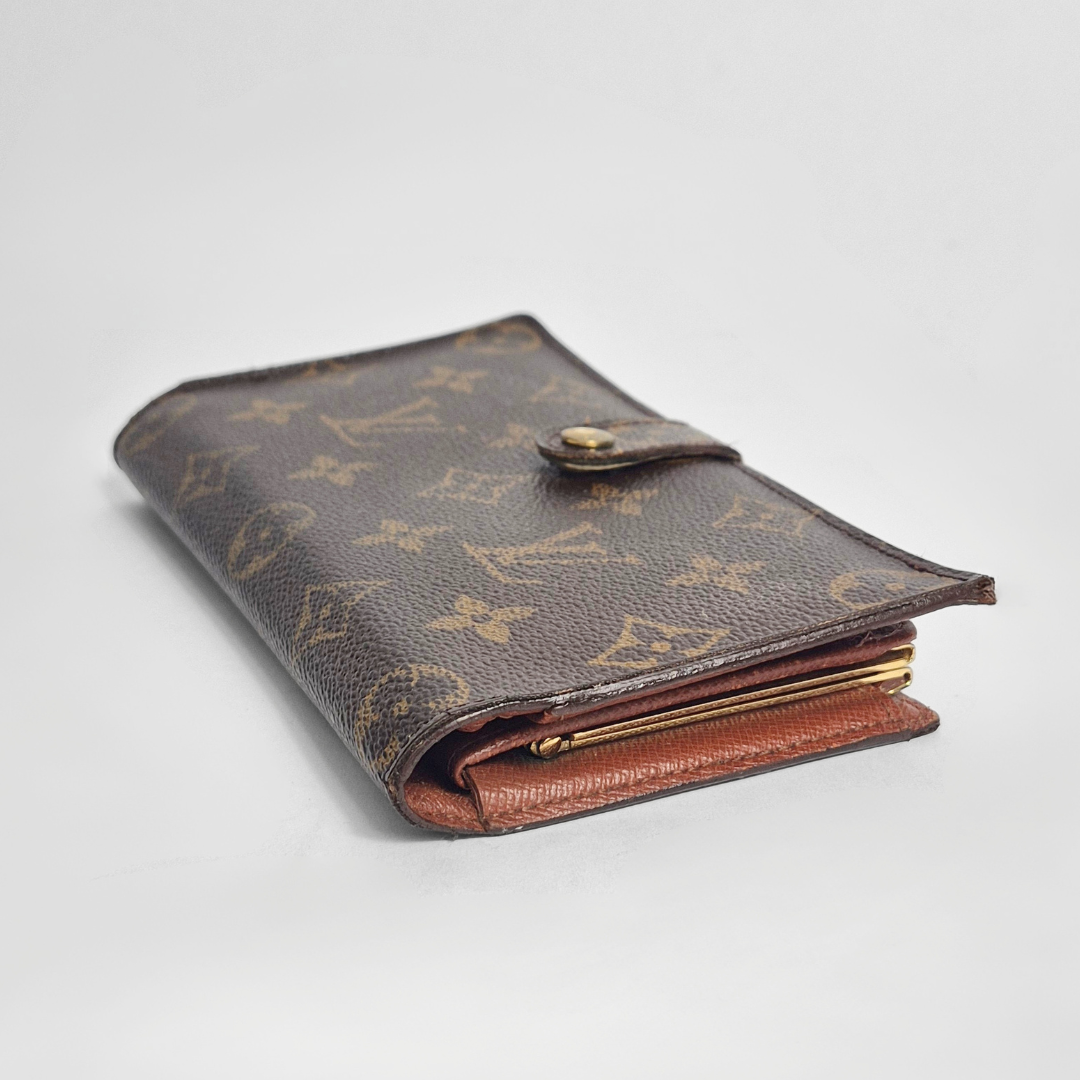 Cartera de piel marrón con detalles dorados sobre fondo gris claro