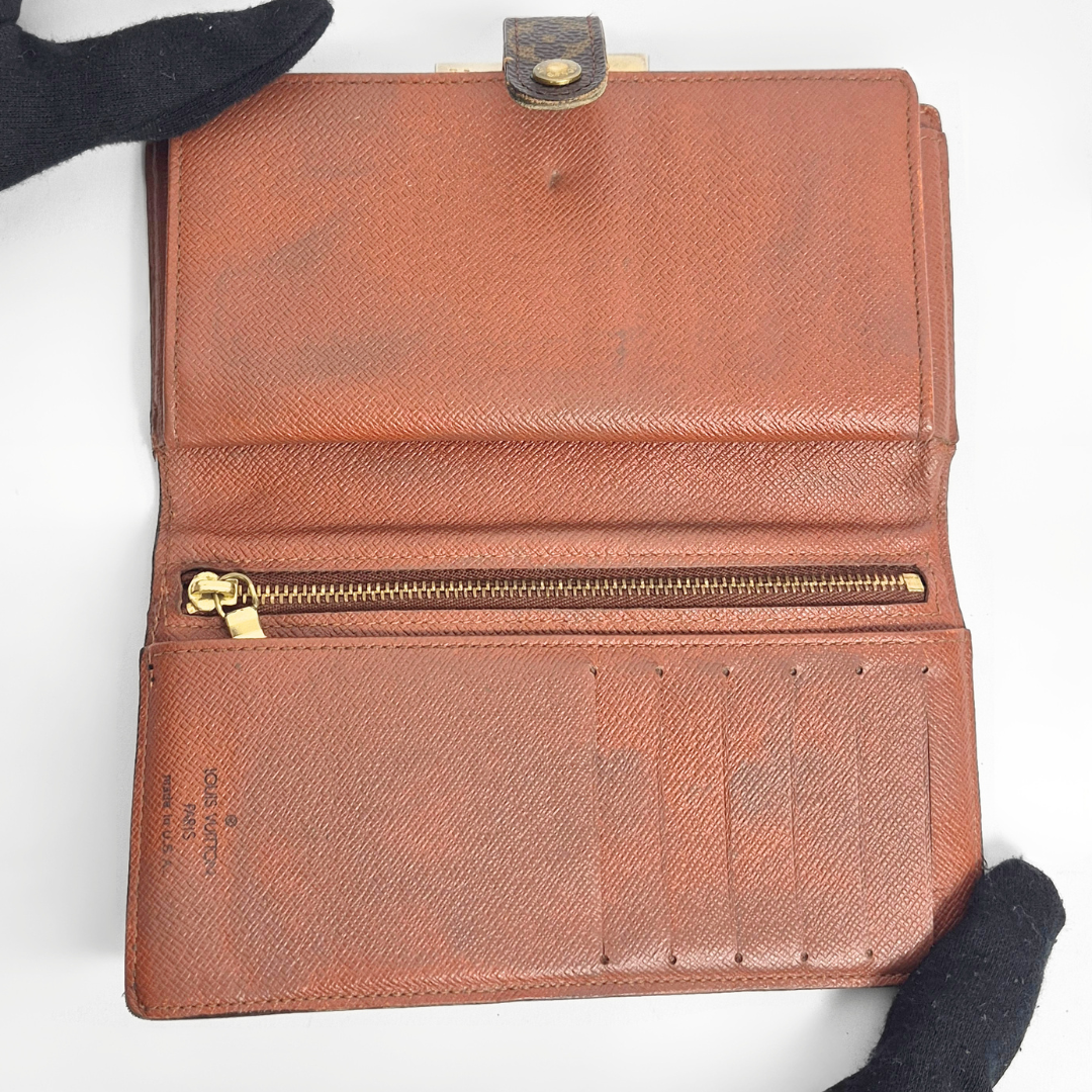 Cartera de piel marrón con cremallera dorada sobre fondo blanco
