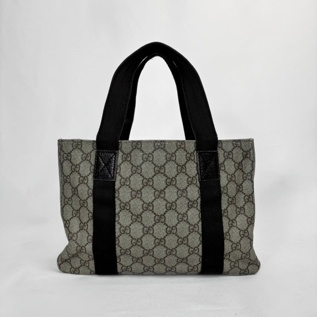 A vintage-style tote bag featuring the classic interlocking GG monogram canvas in gray and brown, with prominent black fabric shoulder straps and black leather trim details.