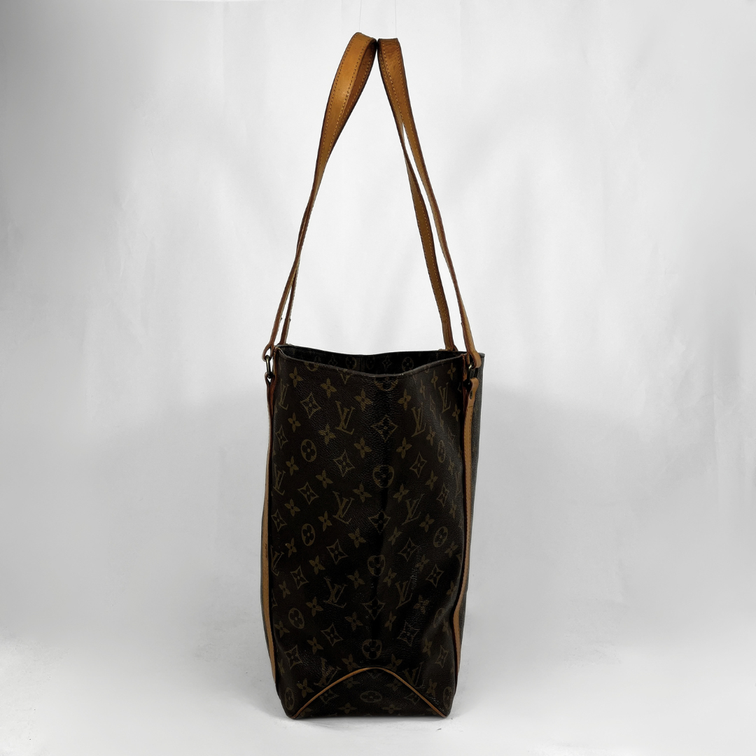 A Louis Vuitton monogram tote bag in dark brown coated canvas with tan leather shoulder straps, shown against a white studio background.