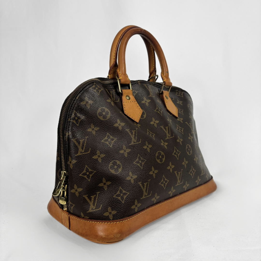 Louis Vuitton monogram canvas handbag with tan leather handles and trim, photographed on a light gray studio background.
