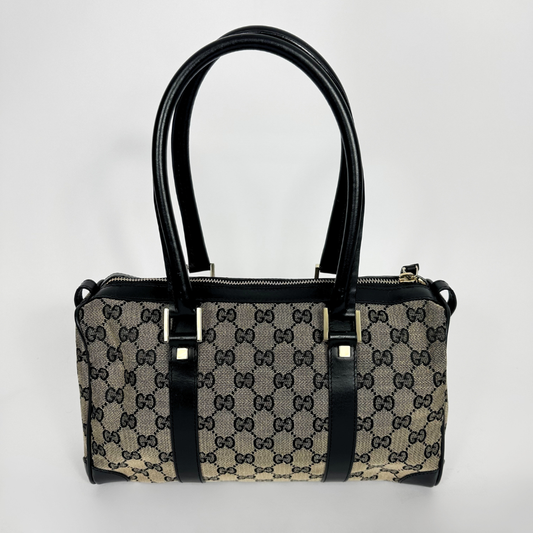 Designer handbag with black handles and trim on a light gray background