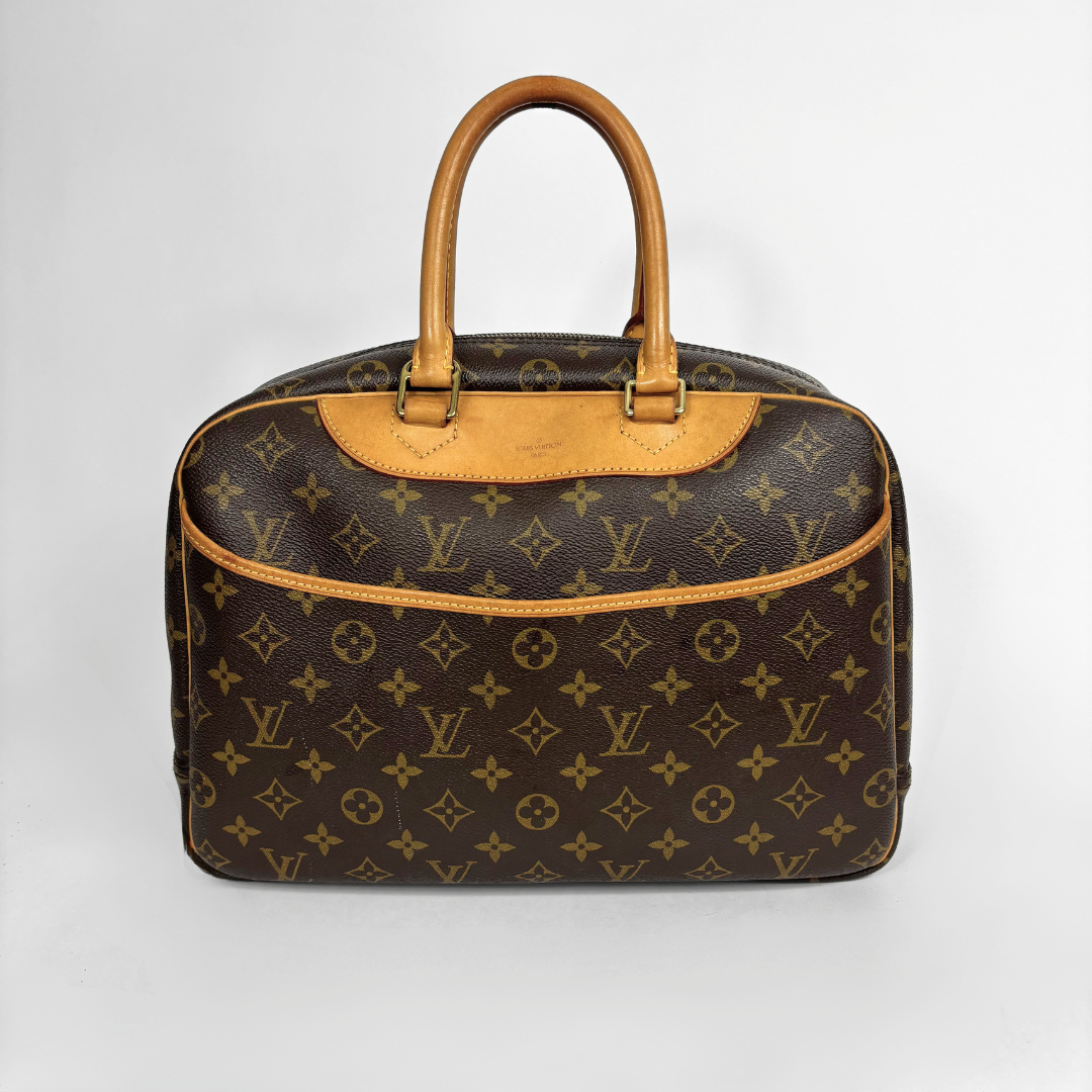 A Louis Vuitton monogram canvas duffel bag with tan leather handles and trim, photographed against a light gray studio background.