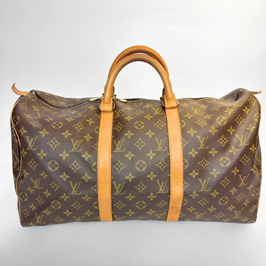 Brown travel bag with tan leather handles on a light gray background