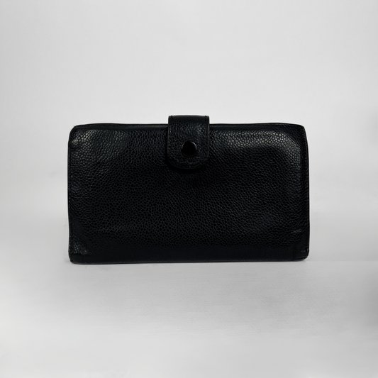 Eine schwarze Clutch-Geldbörse aus genarbtem Leder mit Druckknopfverschluss, fotografiert vor einem neutralen hellgrauen Hintergrund.