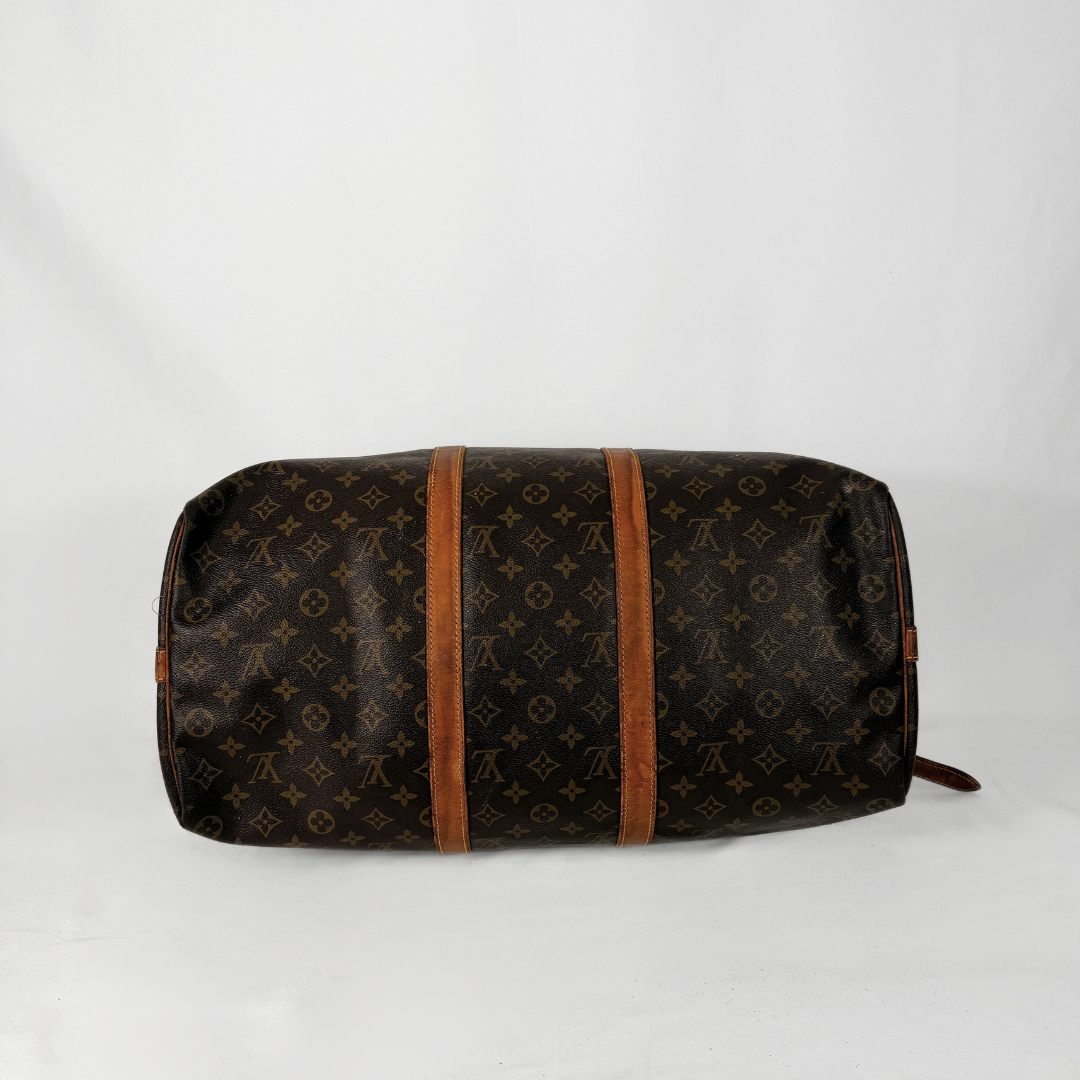 A Louis Vuitton monogram canvas duffel bag in dark brown with tan leather trim, photographed against a plain white background.