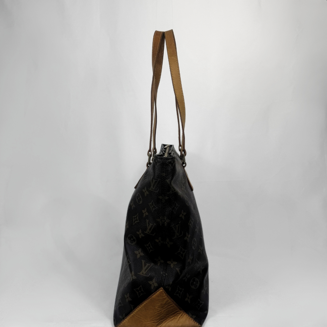A Louis Vuitton black monogram canvas tote bag with brown leather shoulder straps and a brown textured leather base, shown against a plain light gray background.