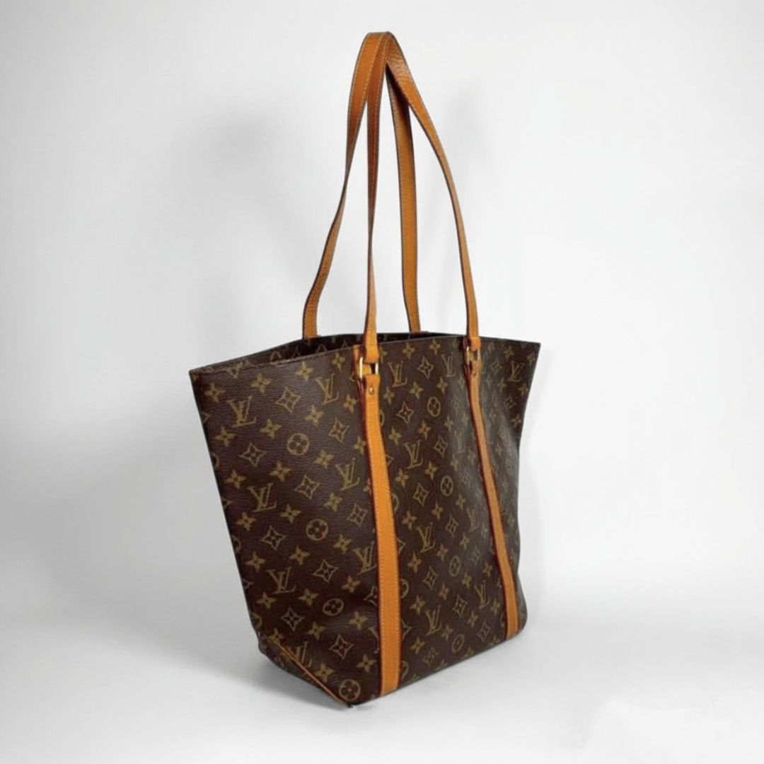 A Louis Vuitton monogram canvas tote bag with tan leather shoulder straps, shown on a light gray background.