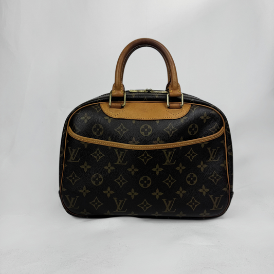Louis Vuitton monogram canvas handbag with brown leather handles and trim, photographed on a light gray studio background.