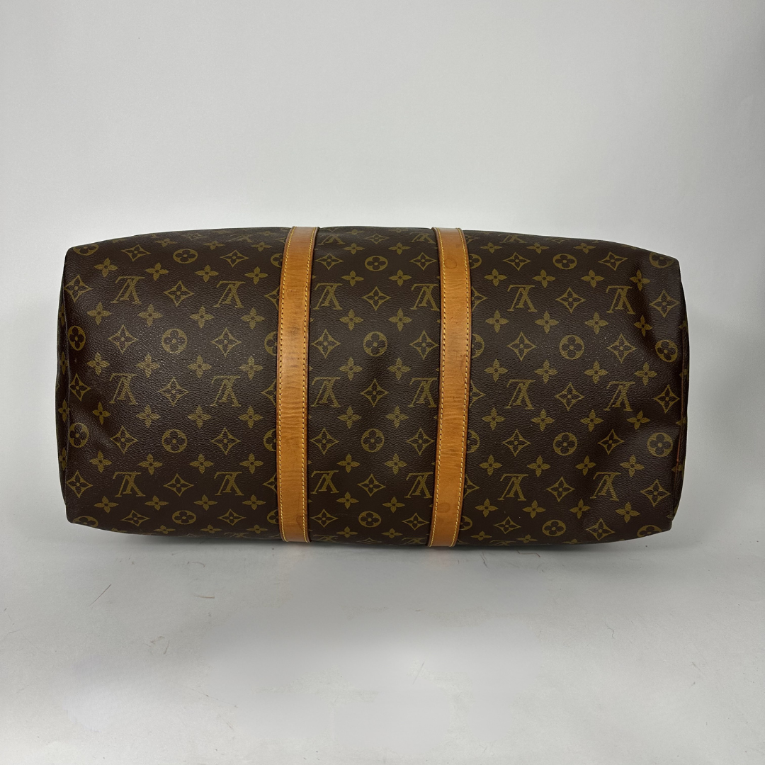 Brown monogram patterned duffel bag with tan leather straps on a white background