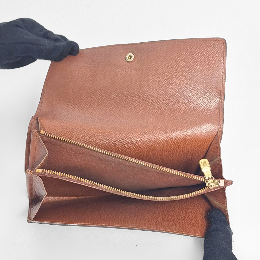 Brown leather clutch bag with gold zipper and clasp on a white background