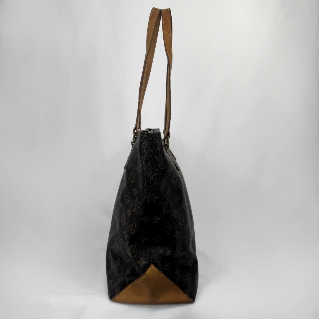 A Louis Vuitton monogram canvas tote bag in black with brown leather trim and shoulder straps, shown from the back against a light gray studio background.