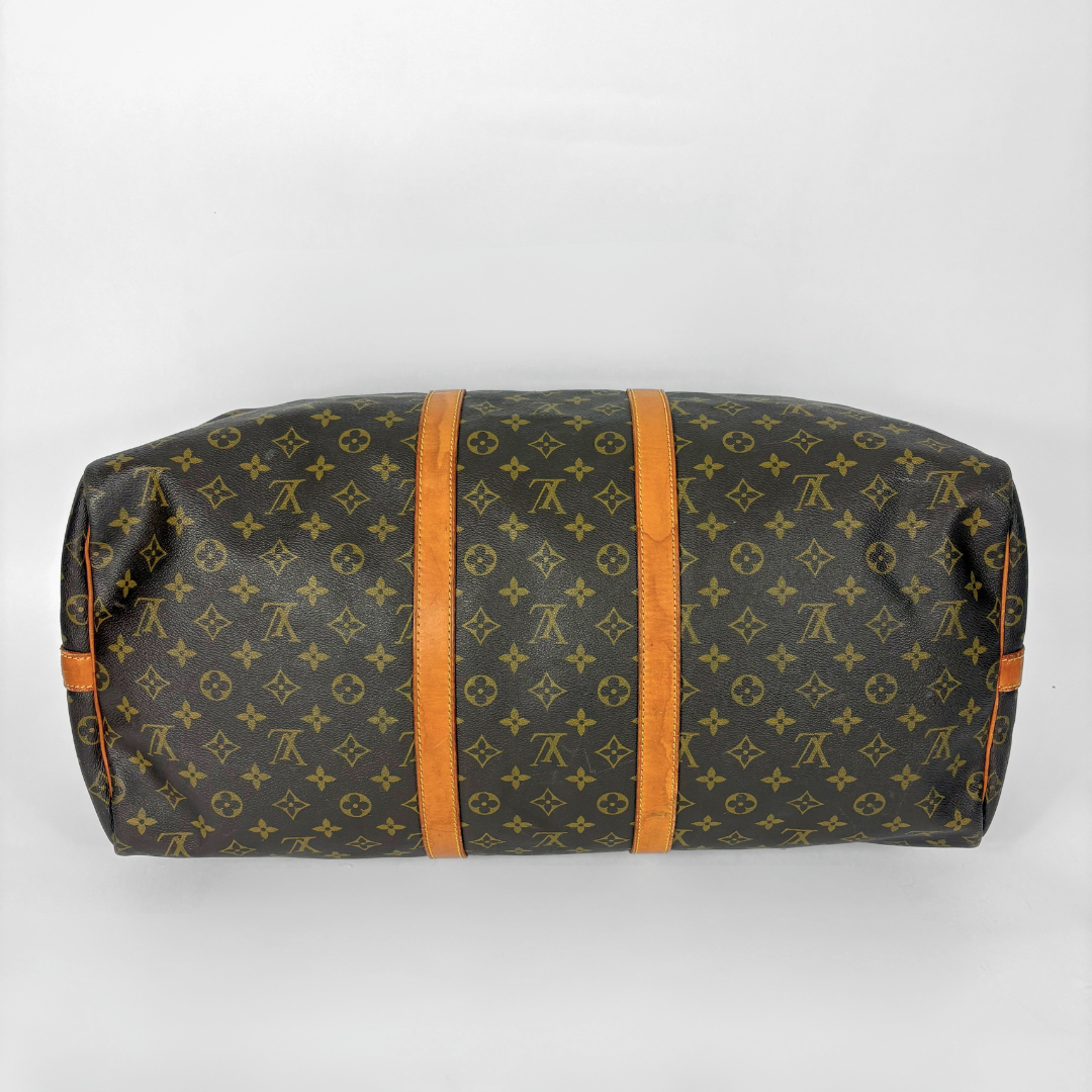 Louis Vuitton monogram travel bag with brown handles on a white background