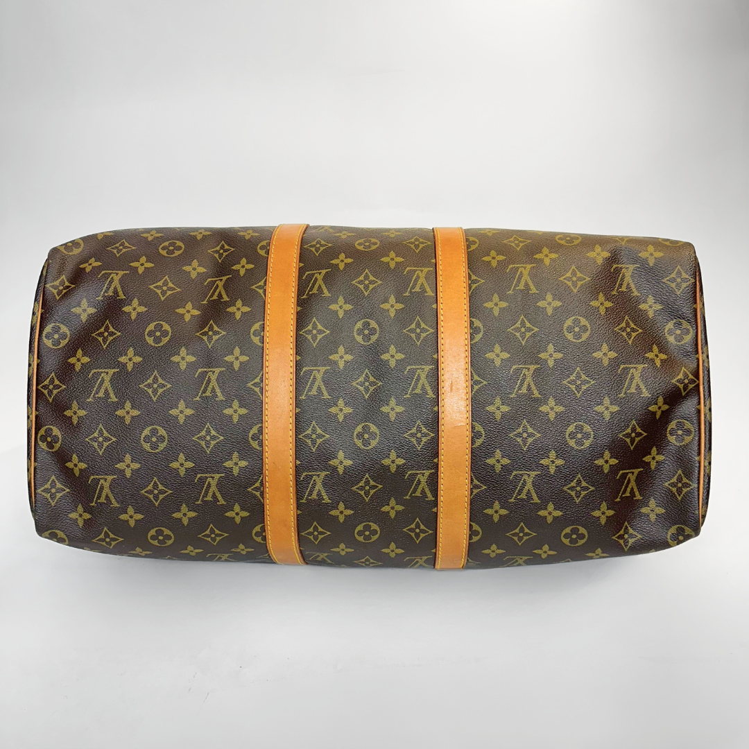 Bolso de viaje marrón con estampado de monograma sobre fondo blanco.
