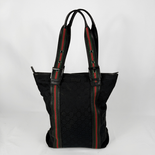 Un nero Gucci Borsa tote caratterizzata dal motivo a righe verdi e rosse, segno distintivo del marchio, sui manici e sui pannelli laterali, su uno sfondo bianco uniforme.