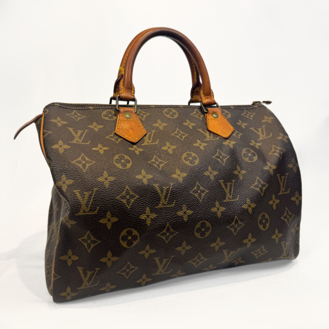 A Louis Vuitton monogram canvas Speedy handbag with brown leather handles and trim, photographed against a plain white background.