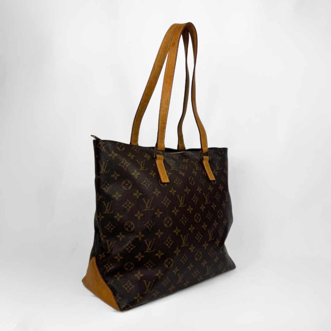A classic Louis Vuitton tote bag in brown monogram canvas with tan leather shoulder straps and bottom corner accents, photographed on a white studio background.