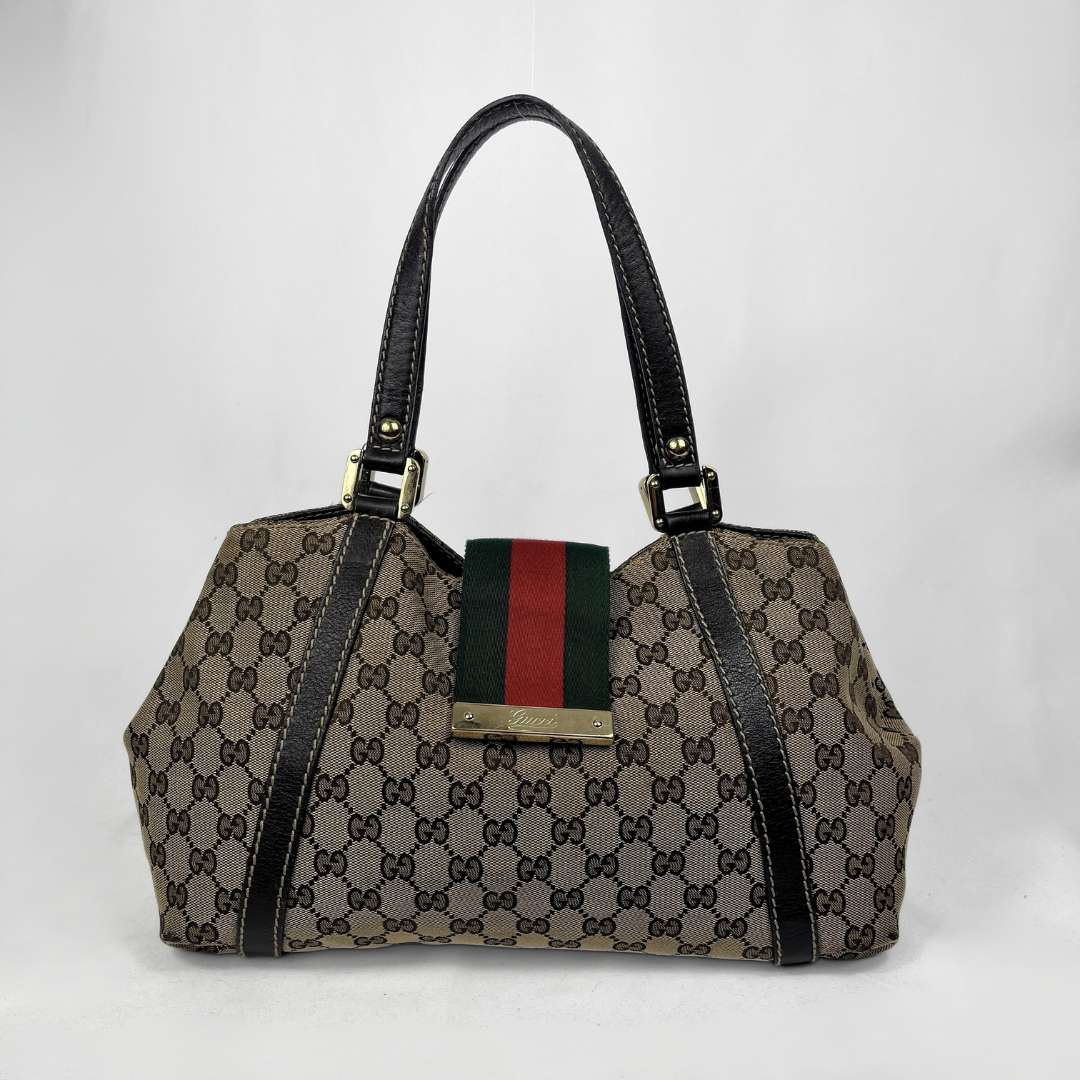 A Gucci handbag in the classic GG Supreme canvas with black leather trim, double shoulder straps, and a signature green and red web stripe detail on the front.