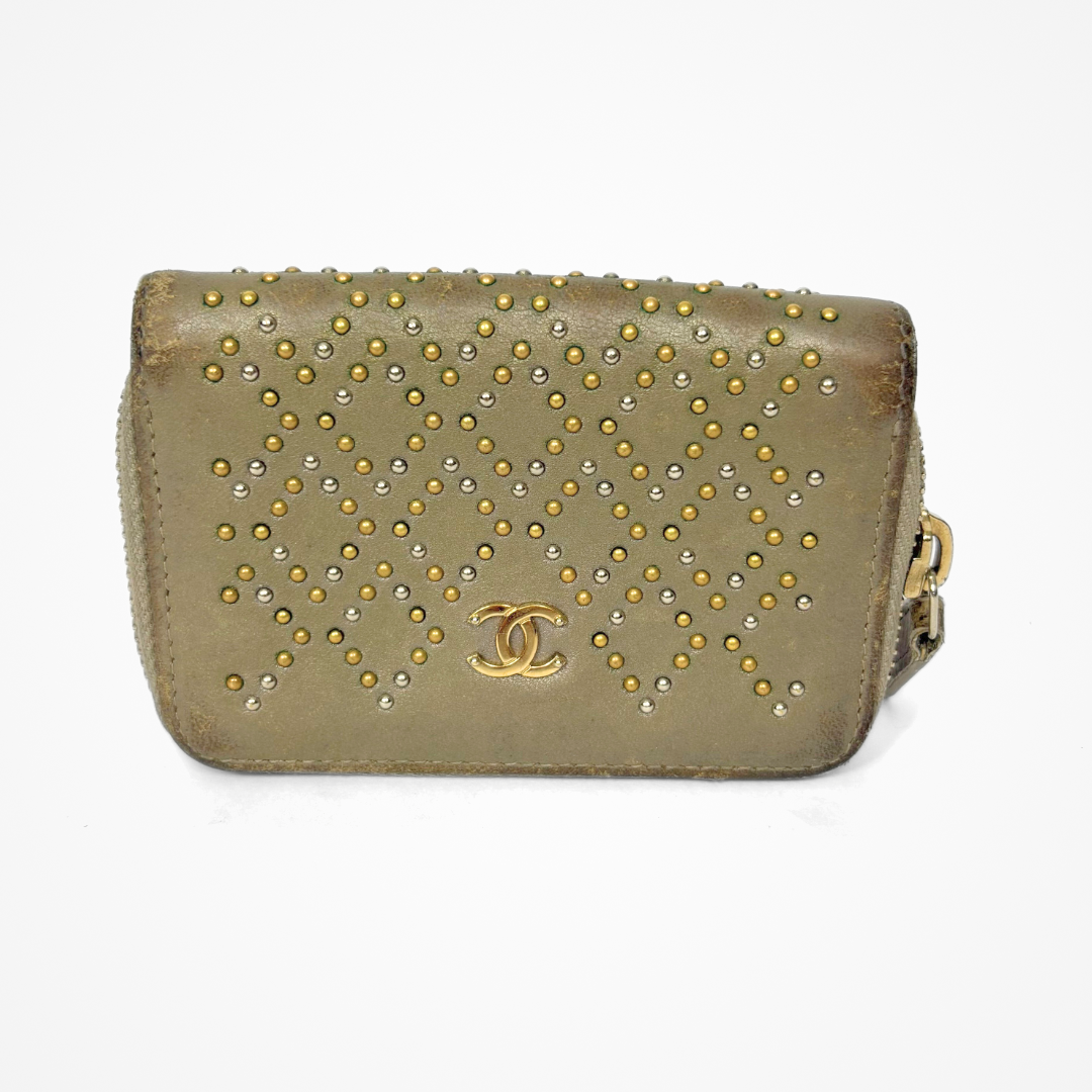 Beige Chanel wallet with gold studs on a white background
