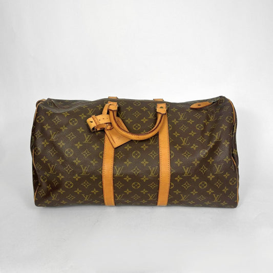 Brown monogram duffel bag with tan leather handles on a white background