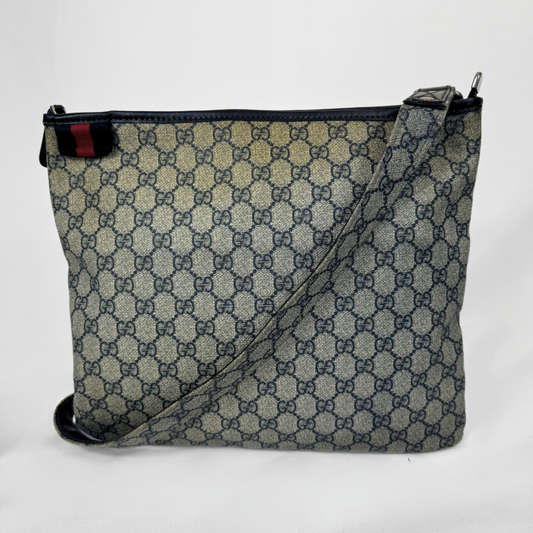 Gucci Borsa a tracolla piatta GG Supreme Web in tela monogrammata con dettagli Web verdi e rossi e finiture in pelle, mostrata su uno sfondo grigio chiaro.