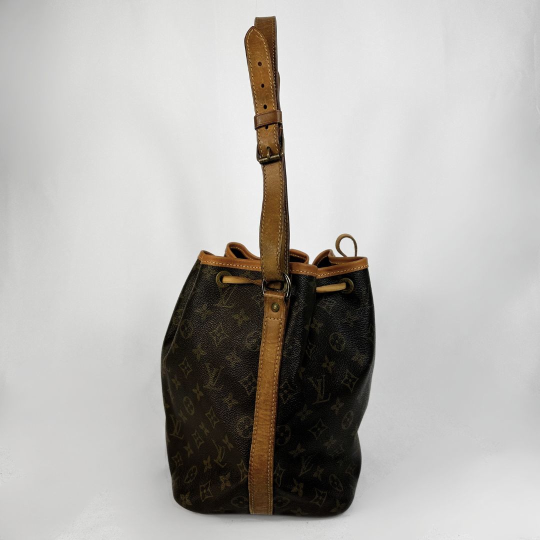 A Louis Vuitton monogram canvas bucket bag with tan leather trim and a matching adjustable shoulder strap, shown against a plain light gray background.
