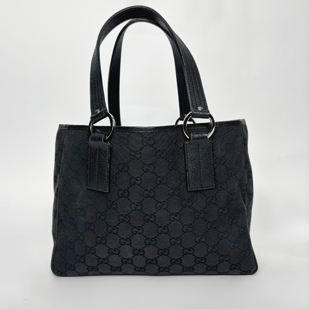 Bolso negro texturizado con el logotipo de la marca sobre fondo blanco.