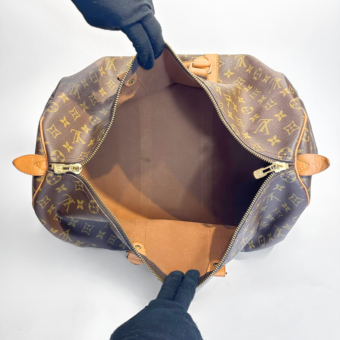 Louis Vuitton Bolso de mano con monograma y parte superior abierta sobre fondo blanco.